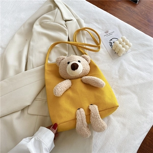 Détail du sac cabas en toile jaune avec ours en peluche 3D sur un blazer crème chic