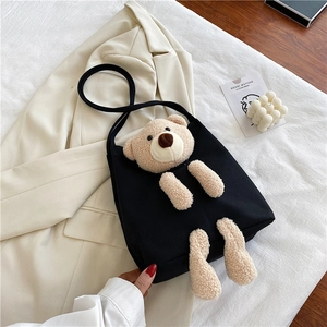 Détail du sac cabas en toile noire avec un ours en peluche 3D sur un blazer de couleur crème