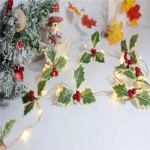 Detail of Christmas garland string light with red berries and snowy pine needles