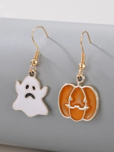 Macro shot of asymmetrical Halloween earrings with orange pumpkin and white ghost charms