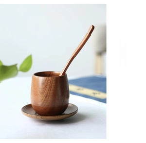 Close-up of wooden tea set with round cup, saucer, and string-wrapped spoon on table