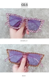 Detail of oversized sunglasses with purple lenses and pink rhinestone-studded frame