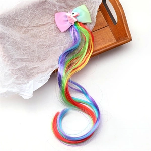 Detail of unicorn hair clip featuring rainbow hair extensions and a pastel ribbon bow