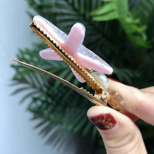 Close-up of golden starfish hair clip with pink resin glitter and a white pearl detail