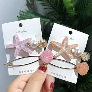 Detailed view of starfish and shell hair clips with pearls and glittery acrylic finish