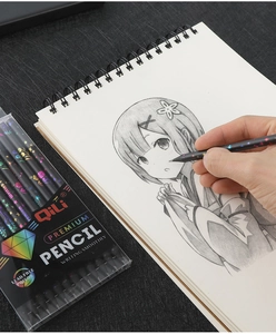 Close-up of black wood cartoon pencils drawing smooth lines on a spiral sketchbook