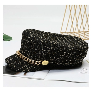 Detail of black tweed newsboy hat with gold chain accent and vintage metallic button
