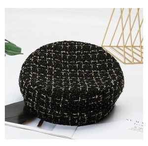 Close-up of black tweed beret with gold metallic thread and woven grid texture
