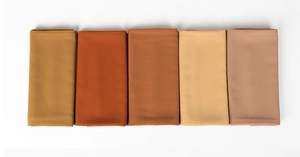 Detail of folded pearl chiffon scarves in mustard, caramel, terracotta, beige and dusty pink