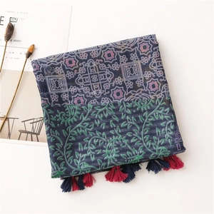 Detailed shot of ethnic cotton scarf with floral patterns and pink tassels on a white desk