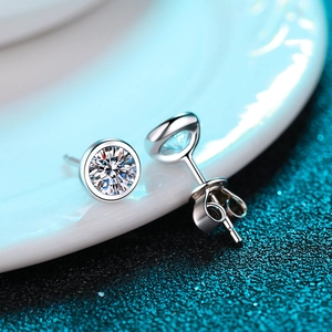 S925 sterling silver stud earrings with round moissanite on a white ceramic plate