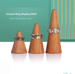 Three conical solid wood ring display stands with natural grain on a white surface