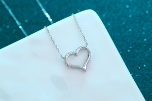 Macro shot of an S925 sterling silver heart-shaped hollow pendant necklace on a geometric base