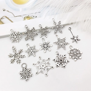 Variety of silver snowflake alloy pendants for DIY jewelry making on white desk