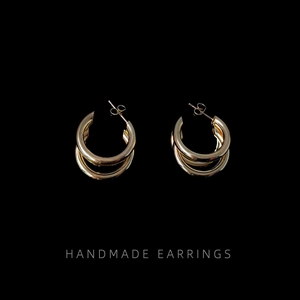 Macro shot of gold double layered circular stud earrings on a dark background