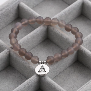 Detailed macro view of 8mm matte grey agate beads and silver Buddha charm in a velvet box