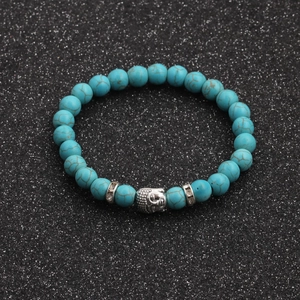 Macro view of turquoise beads with silver Buddha head and sparkling spacers on a black background