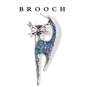 Macro detail of silver cat brooch featuring sparkling blue-green rhinestones