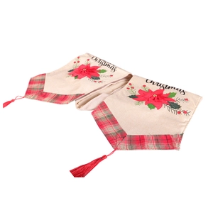 Christmas table runner with red flowers, plaid pattern and tassels on beige cotton linen cloth