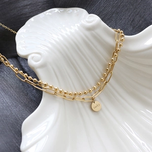 Detail of a double-layered 18K gold plated necklace with a lucky round pendant
