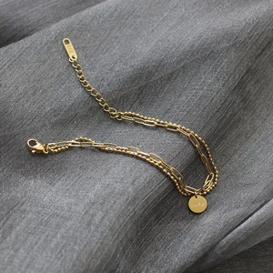 Detail of 18K gold double-layer bracelet with paperclip chain and Lucky pendant