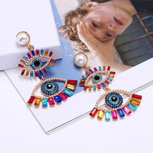Macro detail of Bohemian evil eye earring with colorful crystals and a white pearl
