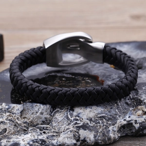 Men's punk leather bracelet with a lion head clasp on dark stone surface