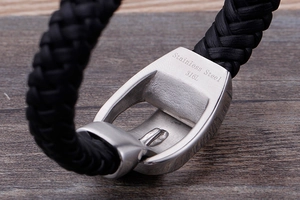 Macro detail of 316L stainless steel lion clasp and black braided leather strap texture