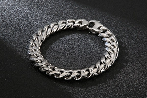 Polished silver Cuban link bracelet with lobster clasp on a dark textured surface
