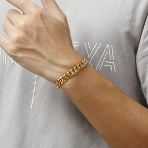 Close-up of a gold stainless steel Cuban link bracelet worn on a model's wrist