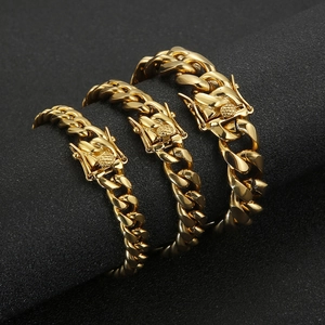 Three widths of golden titanium steel Cuban link bracelets shown on a luxury cylinder display