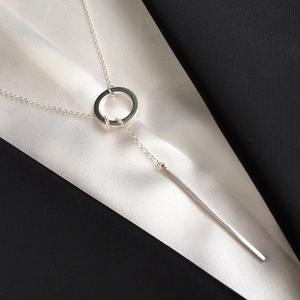 Close-up of minimalist silver stainless steel lariat necklace on black and white silk