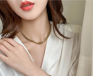 Close-up of gold Cuban chain necklace with a blank rectangular pendant on a model