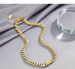 Detailed close-up of a gold Cuban link chain necklace resting on soft grey silk fabric