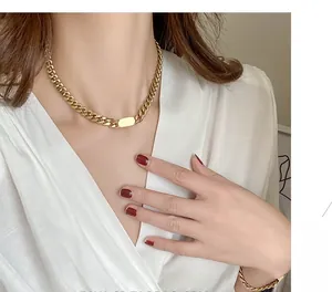 Close-up of a chunky gold titanium steel Cuban chain necklace with a rectangular plate