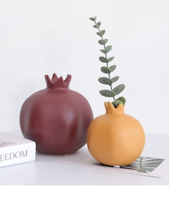 Dettaglio macro dei vasi in ceramica rossa e gialla a forma di melograno con finitura opaca