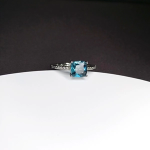 Detailed macro view of a square-cut blue sapphire ring with a side diamond-set silver band