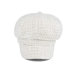 Detail of cream plaid newsboy cap showing tweed fabric texture and top button decoration