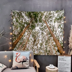 Detail of forest landscape tapestry on wall with fairy lights above a gray sofa