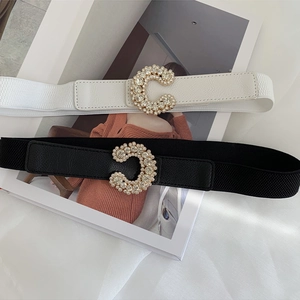 Close-up of black and white elastic belts with crystal-encrusted C-shape floral buckles