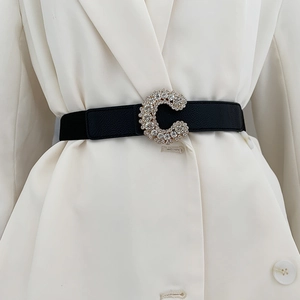 Detail showing a black elastic waist belt with a sparkling C-shape rhinestone buckle