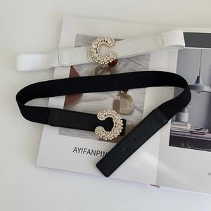 Detailed view of elastic belts with rhinestone C-buckle in black and cream leather
