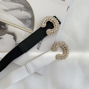 Detail of black and white elastic belts with diamond-encrusted C-shape metal buckles