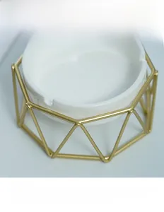Detail of white ceramic ashtray with gold geometric metal frame and fine weld spots