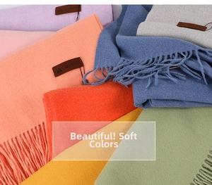Close-up of colorful cashmere-feel scarves with soft fringes and leather brand tags