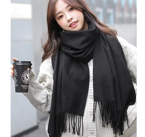 Detailed view of the soft black cashmere scarf texture and long tassel edges on a model