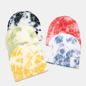 Detail of cable knit texture on colorful tie-dye beanies in a stacked arrangement