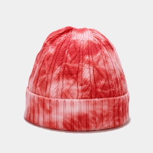 Detail showing the red and white tie-dye knit texture and cable pattern on the beanie hat