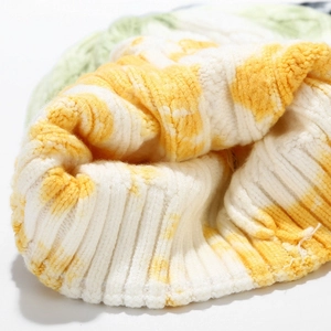 Close-up of tie-dye knit beanie featuring yellow and green yarn with ribbed cuff detail