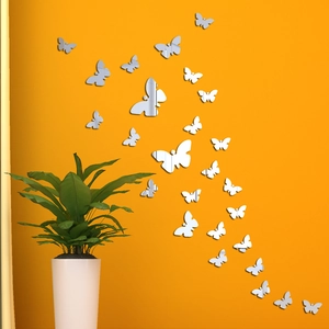 3D silver butterfly acrylic mirror wall stickers for home decor on an orange background